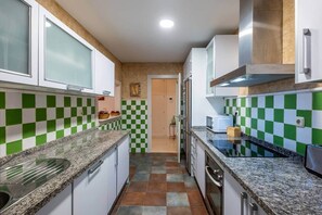 A kitchen with checkered green and white tiles, granite countertops, and white cabinets. - Comeback Un Rayo de Sol (Motril)