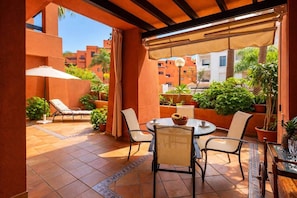 A covered outdoor patio with a round table, chairs, and potted plants. - Comeback Un Rayo de Sol (Motril)