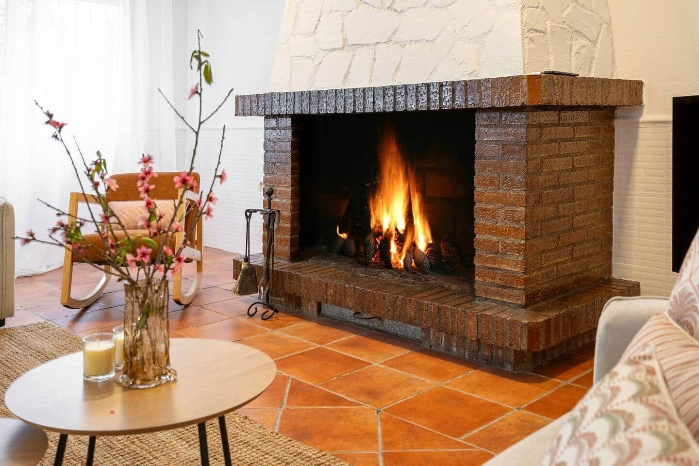Una sala de estar con chimenea, una mesa redonda con velas y un sillón.