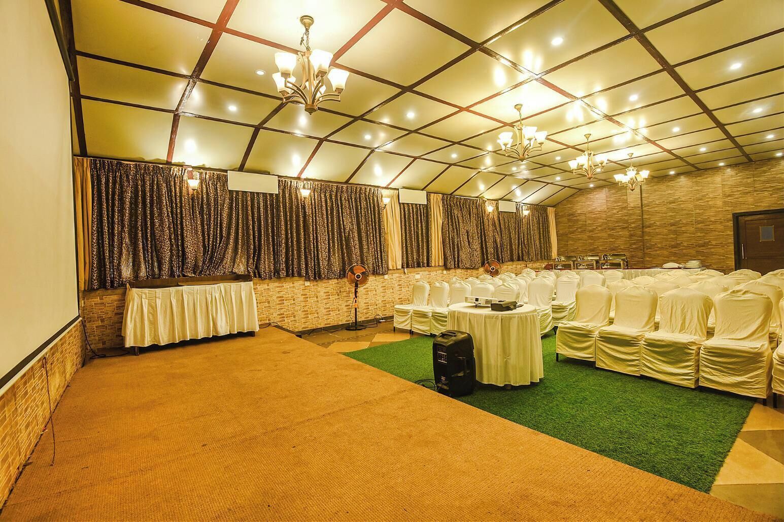 Un salón de banquetes con techo alto, candelabros y filas de sillas cubiertas.