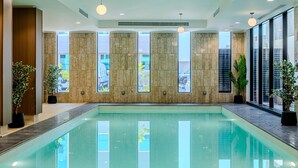 Ein moderner, überdachter Schwimmbereich mit großen Fenstern, Zimmerpflanzen und einem klaren, zeitgemäßen Design.