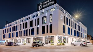 Ein modernes Hotel mit einer auffälligen Beschilderung, großen Fenstern und einem Parkplatz mit mehreren Autos.