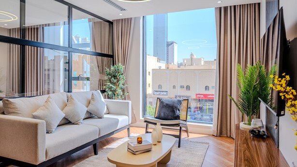 Ein modernes Wohnzimmer mit einer Couch, einem Couchtisch und einem großen Fenster mit Vorhängen.