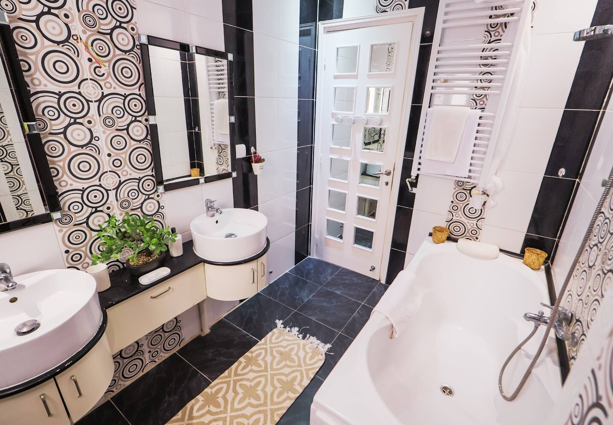 A bathroom with two sinks, a bathtub, and a door with a mirror.