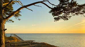 A beach with a wooden bench, a staircase leading to a viewing platform, and a tree. - Öland Idyll loft apartment close to the sea - swimming, surfing, kiting, hiking, cycling! (Mörbylanga)