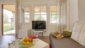 A living room with a sofa, a television, a dining table with a plate of fruit and a glass, and a magazine. - Ferienhaus mit Kamin am Achterwasser in Lutow (Luetow)