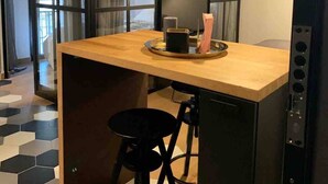 Eine kleine Küchenzeile mit einer Holzarbeitsplatte, einem schwarzen Hocker und einem schwarzen Schrank.