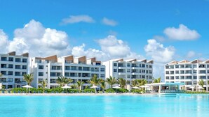 A hotel with multiple white buildings, a pool, and palm trees. - Modern 2Bdrm Apt Lagoon-Style Beach  Downtown (Punta Cana)