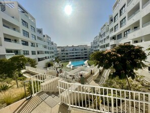 Ein moderner Apartmentkomplex mit einem zentral gelegenen Schwimmbad, mehreren Balkonen und einem gepflegten Garten.