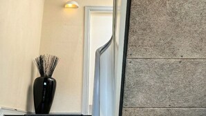 A staircase with a textured wall, a black vase with sticks, and a white door at the bottom. - Garden Suite - 1BR - Esbjerg Island (Esbjerg)