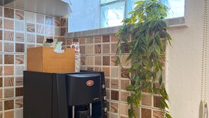 A kitchen with a coffee machine, a window with blinds, a potted plant, and a tiled backsplash. - Stay in a comfortable apartment - Valentino Apartment (Shkodër)
