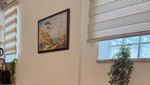 A room with a red sofa, a ukulele, a framed painting, and a potted plant. - Stay in a comfortable apartment - Valentino Apartment (Shkodër)