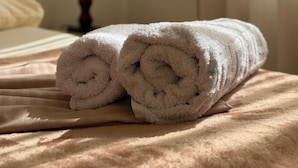 A neatly made bed with rolled towels, a lamp, and a window with curtains. - Stay in a comfortable apartment - Valentino Apartment (Shkodër)