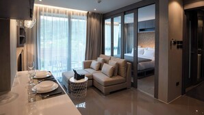 Een moderne hotelkamer met een bank, een zithoek met een tafel gedekt voor twee personen en een bed met uitzicht.