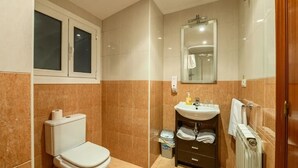 Een badkamer met toilet, wastafel, spiegel en douche.