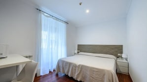 Een slaapkamer met een bed, een bureau en een stoel.