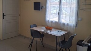 En matplats med ett bord, stolar, en korg och ett fönster med en gardin.