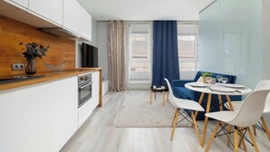 Eine moderne Küche mit weißen Schränken, einer Holzarbeitsplatte und einem eingebauten Backofen. Es gibt einen Essbereich mit einem runden Tisch und weißen Stühlen.