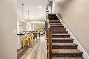A staircase with wooden steps and a handrail, leading to a dining area with a high ceiling and pendant lighting. - Coral Ridge 2076, Near Golf Course, Community Amenities! (Washington)
