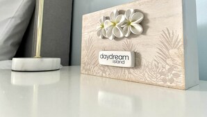 Een houten blok met een bloemenpatroon en de tekst 'daydream island' op een tafel.