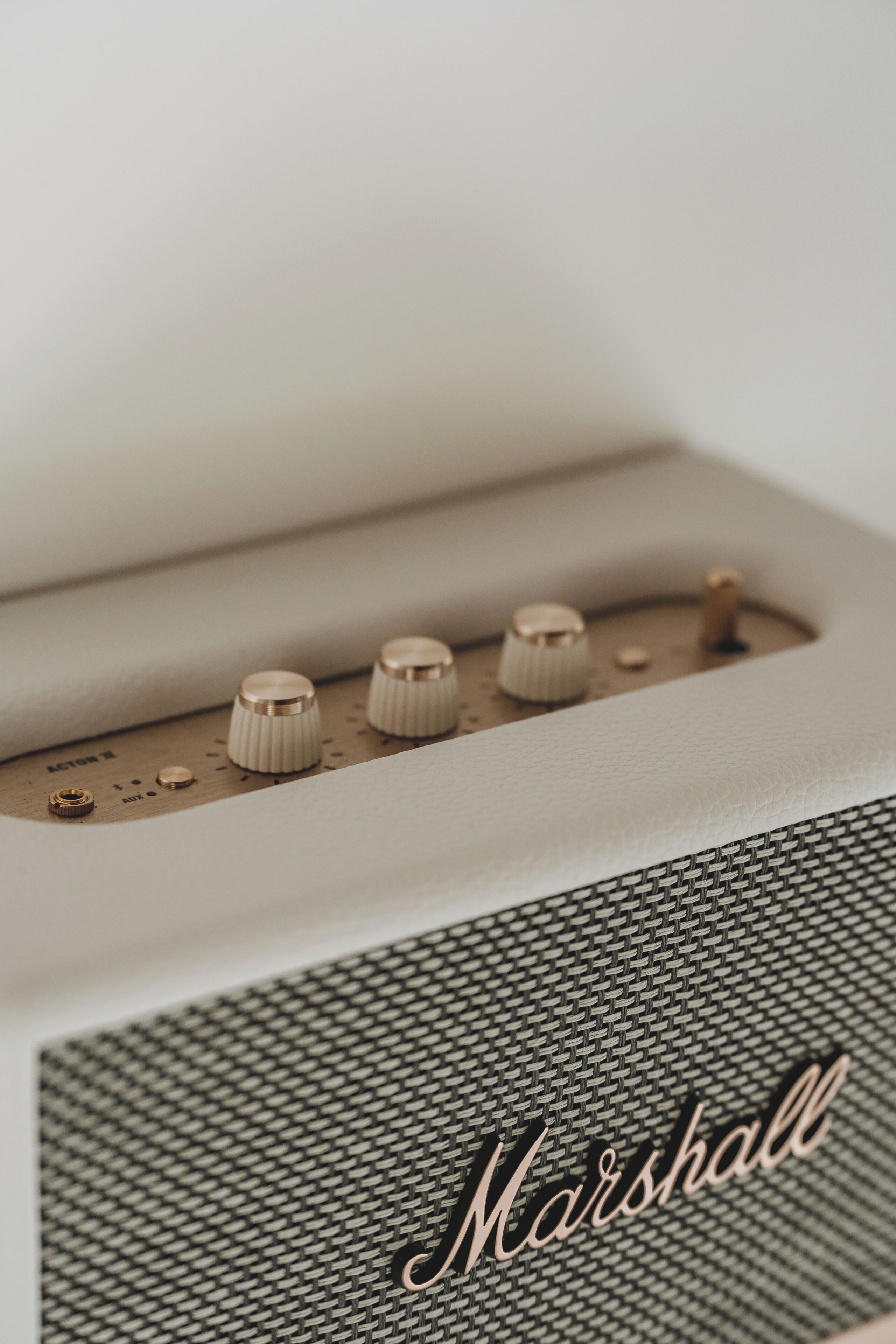 A close-up of a vintage Marshall speaker with four knobs and a mesh front panel.