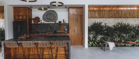 A modern kitchen with a central island, wooden cabinets, and a marble countertop.