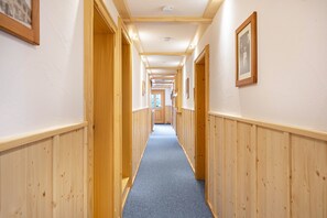 Ein Korridor mit Holzwandverkleidung, gerahmten Bildern an den Wänden und einem blauen Teppich.