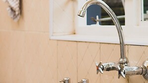 A kitchen sink with a faucet, a window with blinds, and a towel hanging on the wall.
