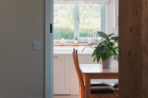 Une cuisine avec une fenêtre, un évier, une plante en pot et des chaises en bois.