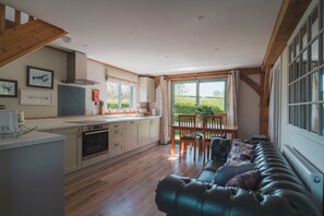 Eine moderne Küche mit Holzbalken, einem Essbereich mit Aussicht und einem Ledersofa.