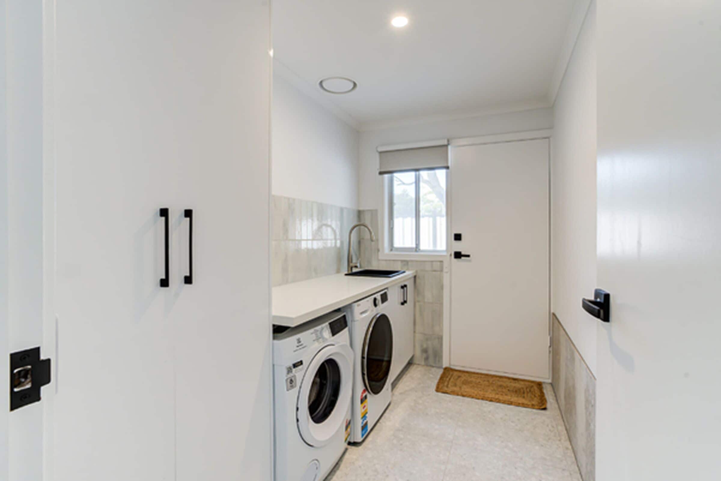 A laundry room with a washing machine, dryer, and sink.