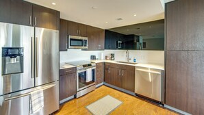 Une cuisine moderne dotée d’appareils électroménagers en acier inoxydable, de meubles en bois et d’un four à micro-ondes encastré.