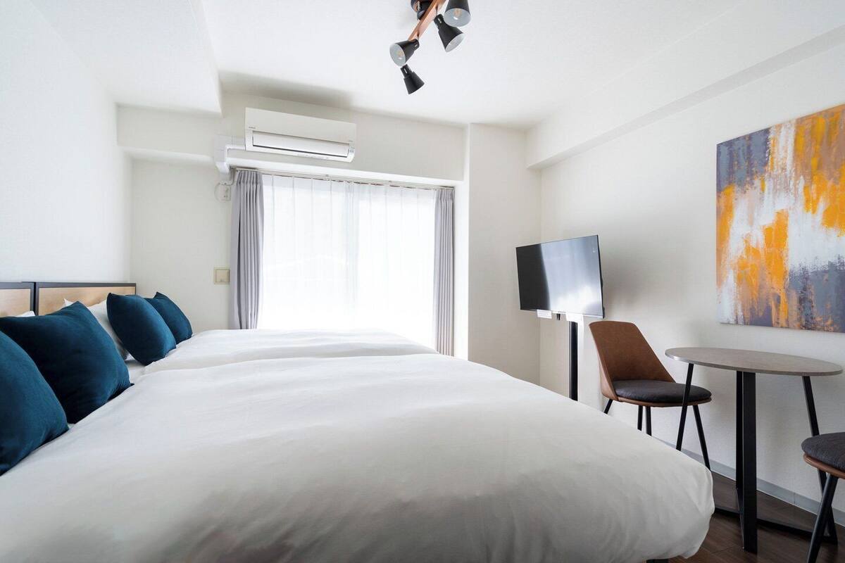 A hotel room with a large bed, a TV, a small table, and a painting on the wall.