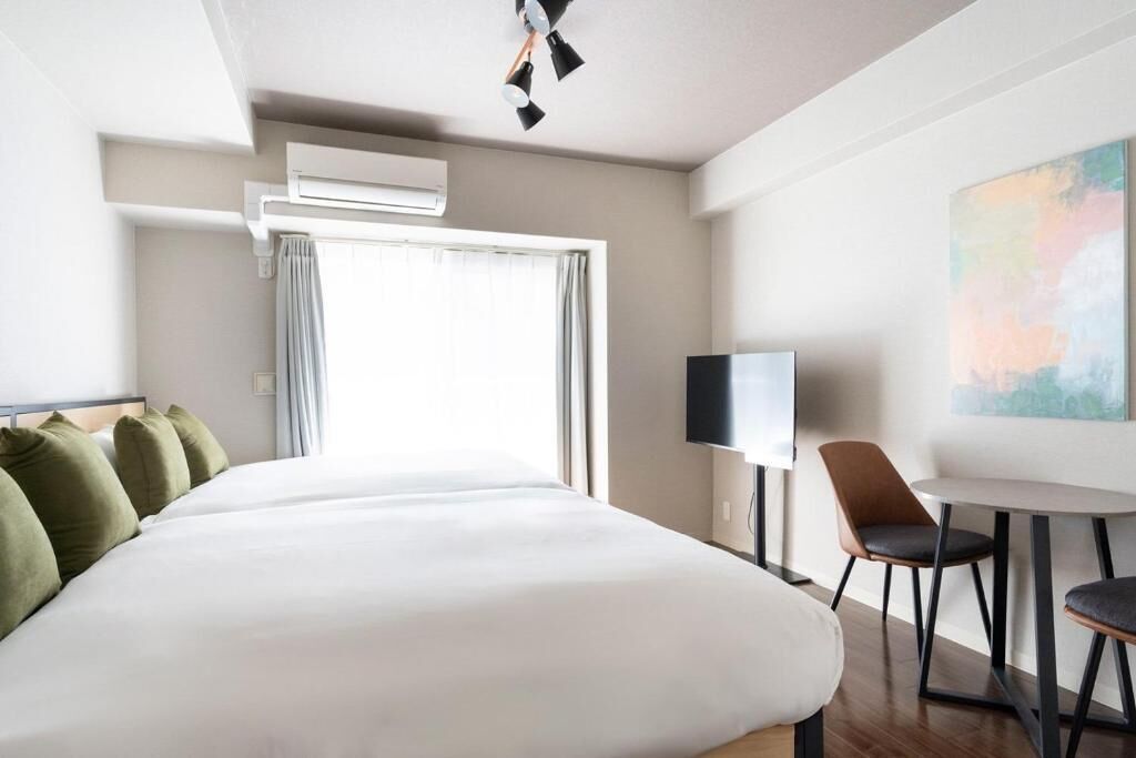 A hotel room with a large bed, a flat-screen TV, a small table, and a chair.