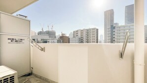 Vista da cidade a partir de uma varanda com grade de metal, uma porta e um respiradouro.
