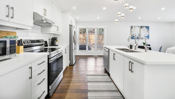 A modern kitchen with white cabinetry, stainless steel appliances, and a large window. - Luxury Estate+Renovated 3 BD+65" TV+WFH+Sleeps 9 (Kitchener)