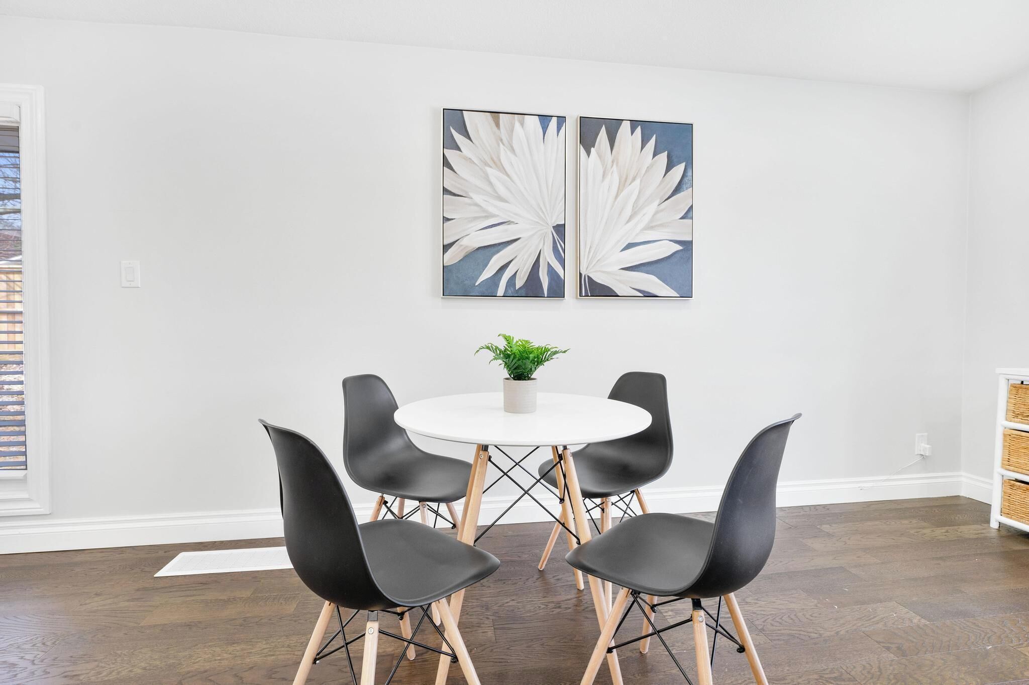 Un espace repas comprenant une table ronde, quatre chaises noires et deux grandes œuvres d’art murales.