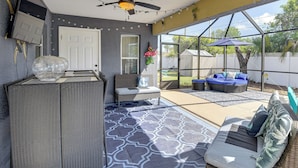 A covered patio with a ceiling fan, string lights, a seating area with cushions, and a view of the backyard. - Patio & Poolside Relaxation! Palm Coast Getaway (Palm Coast)