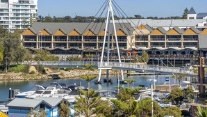 A marina with boats, a bridge, and a building with multiple balconies. - Coastal Studio | City & Ocean Views, Walk to Beach (Mandurah)