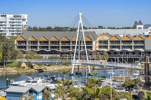 A marina with boats, a bridge, and a building with multiple balconies. - Coastal Studio | City & Ocean Views, Walk to Beach (Mandurah)