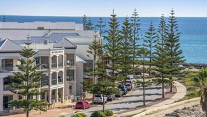 A coastal hotel with a modern design, featuring a prominent balcony, a parking area, and a view of the sea. - Coastal Studio | City & Ocean Views, Walk to Beach (Mandurah)