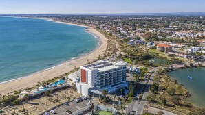 A coastal hotel with a pool, tennis court, and a view of the beach and ocean. - Coastal Studio | City & Ocean Views, Walk to Beach (Mandurah)