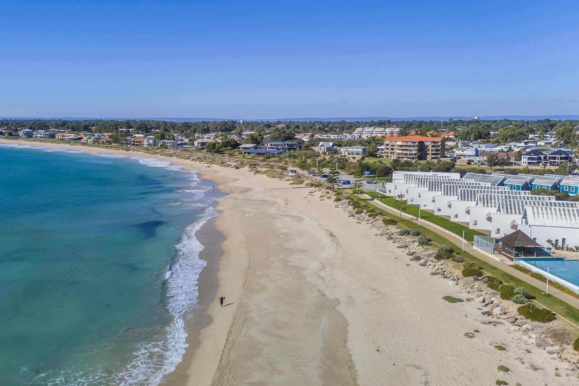 A coastal resort with beachfront properties, a sandy beach, and a clear view of the ocean.