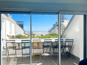 Ein Balkon mit Meerblick, einem Tisch und mehreren Stühlen.