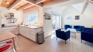 A modern kitchen with a large window, a dining area with blue chairs, and a view of the outside.