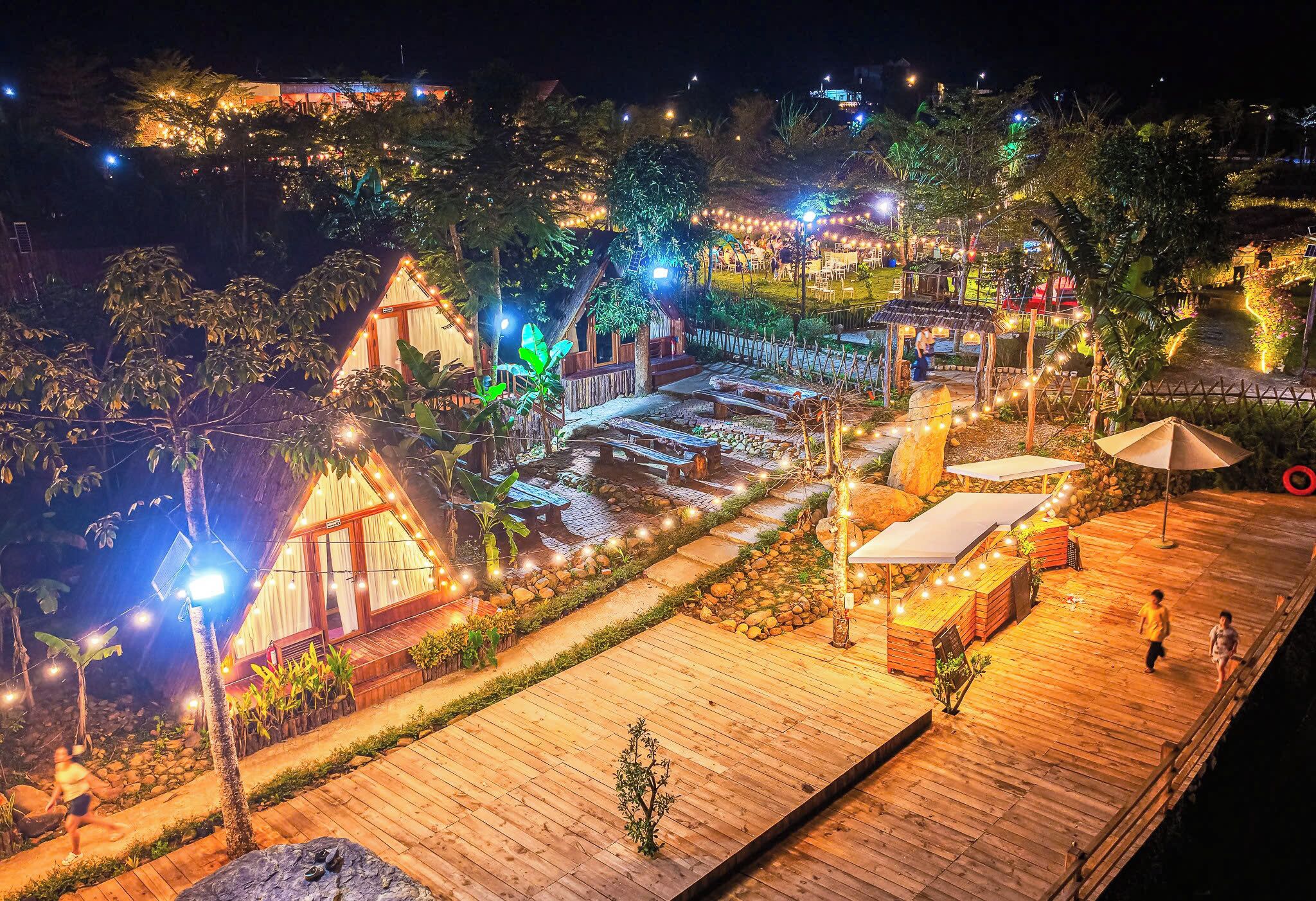 A wooden deck with a small building, string lights, and a pathway.