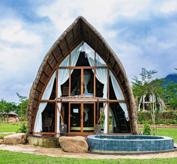 A thatched-roof building with large windows and a small pool. - LEAF VILLAGE & FARM LÀNG LÁ (Da Nang)