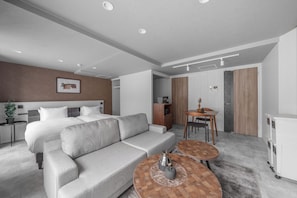 Ein modernes Hotelzimmer mit Bett, Sofa, Esstisch und einer kleinen Küchenzeile.