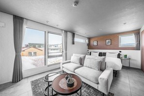 A modern hotel room with a sofa, a small round table, a bed, and large windows. - GRAN HILLS 202 / Chitose City Hokkaidō (Chitose City)