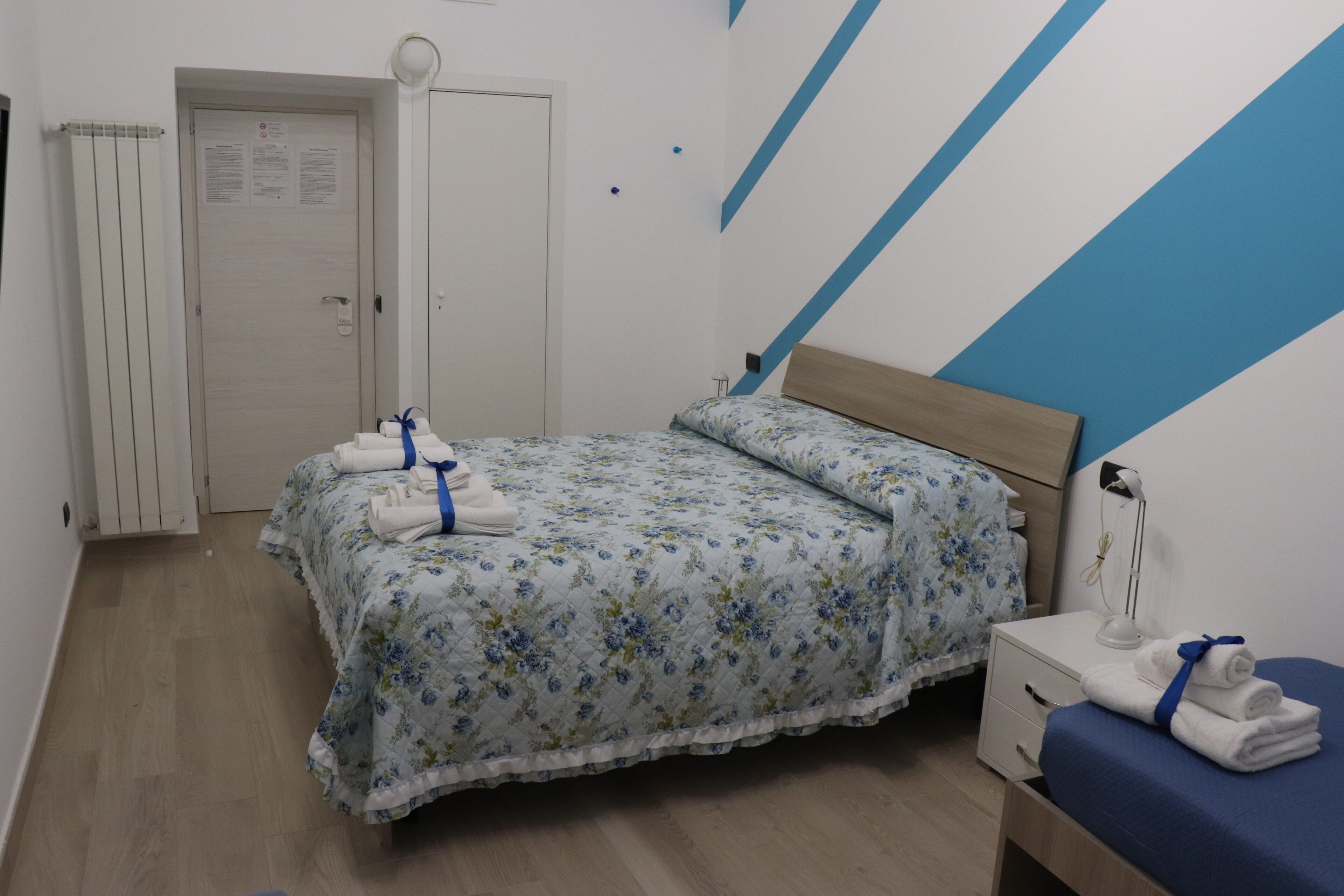 Une chambre à coucher avec un lit, une table de chevet, une commode, une porte et un radiateur.
